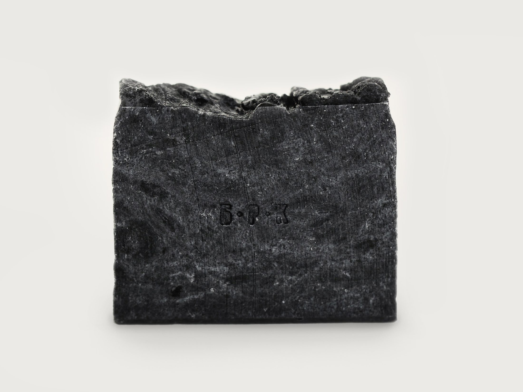 Hand-cut charcoal soap bar with Б·Р·К stamped into its face
